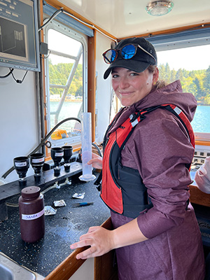 Chandra Schulte holding a graduated cylinder aboard a boat